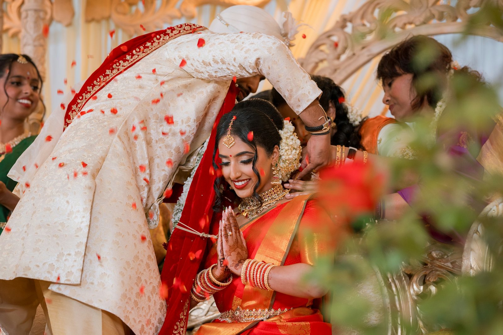 Petals falling, hearts full — two families become one. Bride smiling during a Hindu wedding ceremony with falling petals